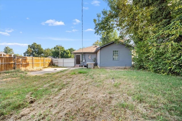 rear view of property featuring a lawn and a fenced backyard
