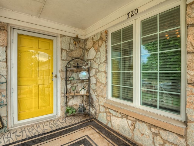 doorway to property featuring a porch and stone siding