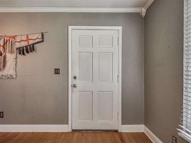 doorway featuring baseboards, wood finished floors, and crown molding