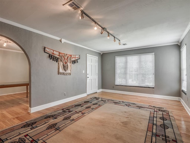 entryway with rail lighting, crown molding, visible vents, arched walkways, and wood finished floors