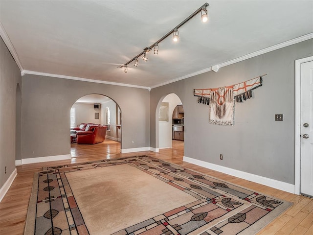foyer featuring wood finished floors, crown molding, and arched walkways