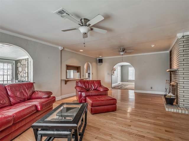 living room with light wood finished floors, ceiling fan, visible vents, and arched walkways