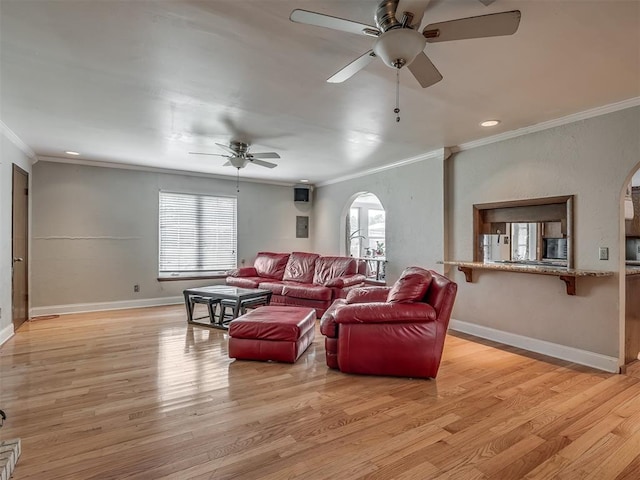 living area featuring arched walkways, a ceiling fan, light wood finished floors, and crown molding