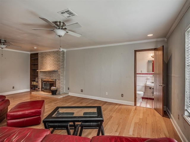 living room with visible vents, baseboards, wood finished floors, a ceiling fan, and built in shelves