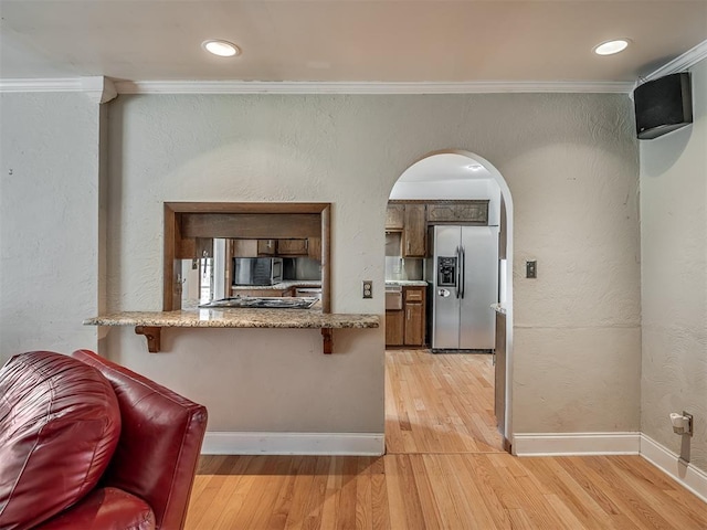 kitchen with light wood-style flooring, appliances with stainless steel finishes, arched walkways, ornamental molding, and a peninsula