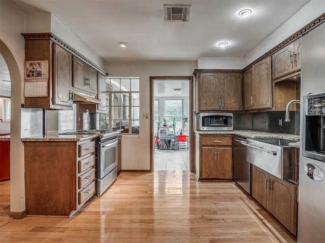 kitchen featuring stainless steel appliances, light wood-type flooring, visible vents, light countertops, and arched walkways