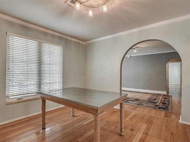 unfurnished dining area with crown molding, arched walkways, wood finished floors, and baseboards