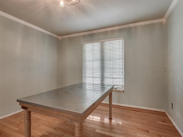 unfurnished dining area featuring crown molding, wood finished floors, and baseboards