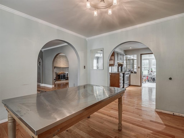 interior space with ornamental molding, arched walkways, baseboards, and light wood-type flooring