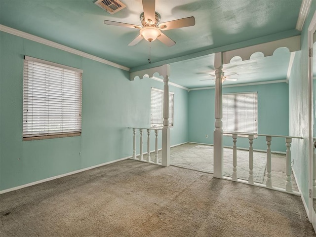 spare room with crown molding, carpet flooring, visible vents, plenty of natural light, and a ceiling fan
