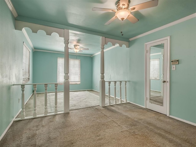 empty room with crown molding, carpet flooring, ceiling fan, baseboards, and ornate columns
