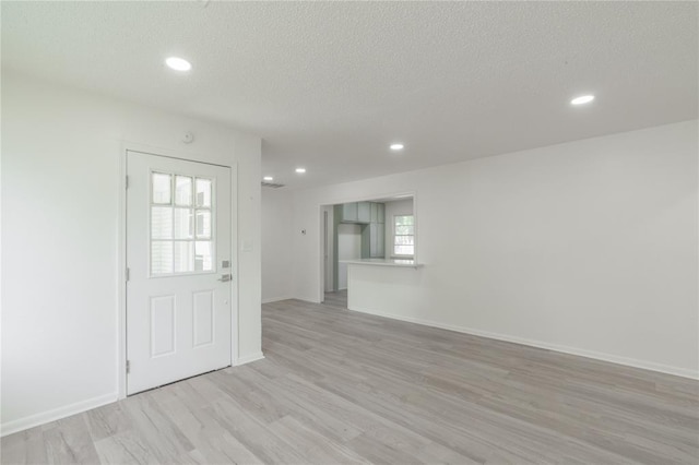 unfurnished room with recessed lighting, light wood-style floors, and a textured ceiling