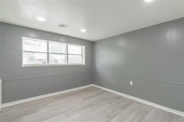 spare room with recessed lighting, wood finished floors, baseboards, visible vents, and a textured ceiling