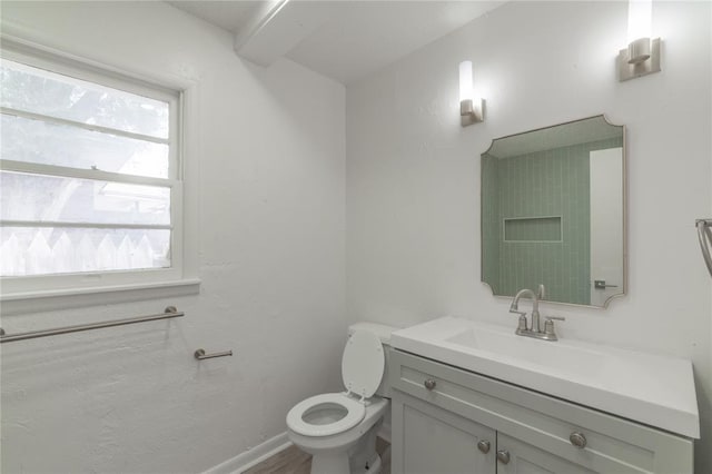 bathroom with toilet, wood finished floors, vanity, and baseboards