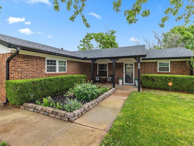 ranch-style home featuring brick siding, roof with shingles, and a front yard