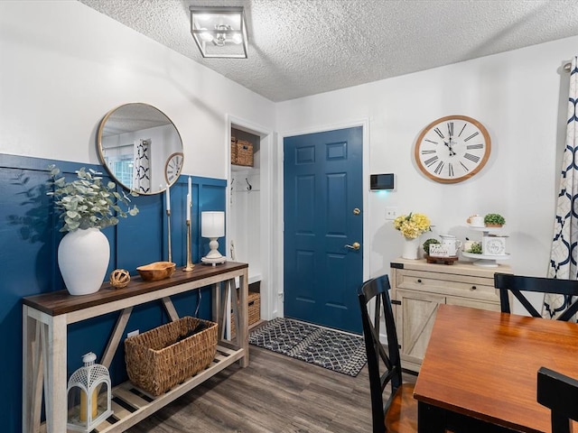 entrance foyer featuring a textured ceiling, wood finished floors, and a wainscoted wall