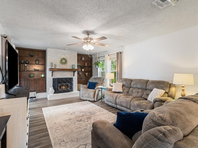 living room featuring visible vents, a ceiling fan, a textured ceiling, and wood finished floors