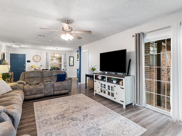 living room featuring ceiling fan, a textured ceiling, visible vents, and wood finished floors