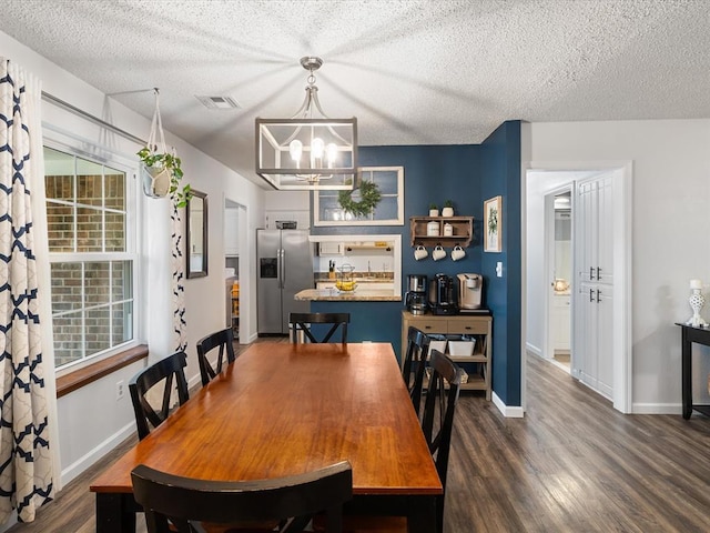 dining area with visible vents, a textured ceiling, dark wood finished floors, and a notable chandelier
