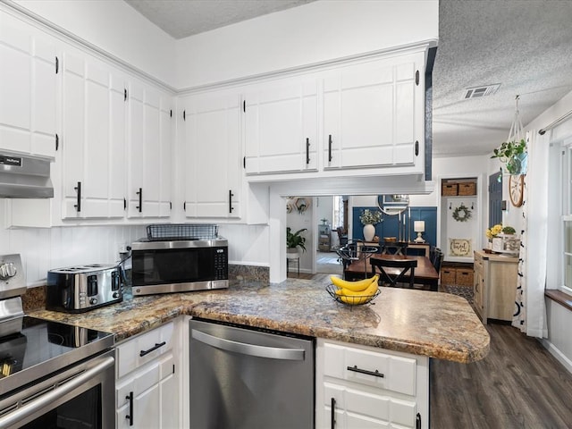 kitchen with white cabinets, dark wood-style flooring, appliances with stainless steel finishes, a textured ceiling, and under cabinet range hood