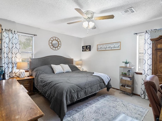 bedroom featuring visible vents, a textured ceiling, light carpet, and multiple windows