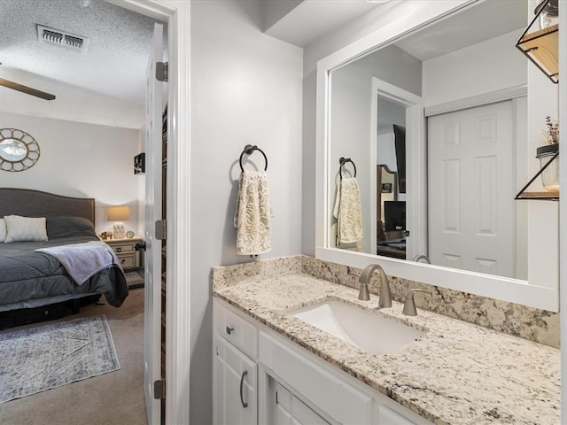 ensuite bathroom featuring visible vents, vanity, ensuite bathroom, a textured ceiling, and a ceiling fan