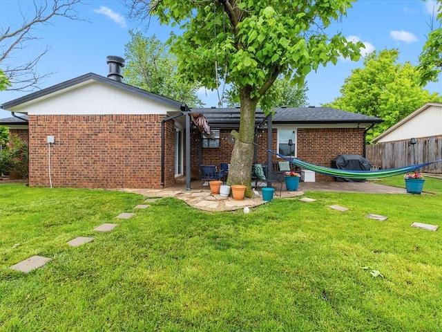 back of house featuring a lawn, brick siding, and fence