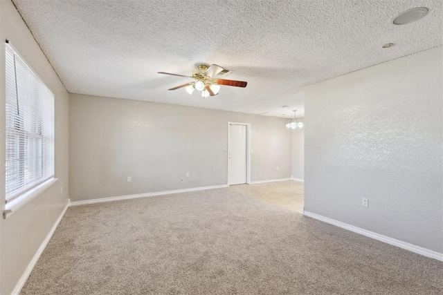 586 Seikel Dr, Choctaw, OK 73020 - spare room with light carpet, a ceiling fan, a chandelier, baseboards, and a textured ceiling