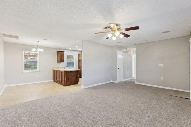 586 Seikel Dr, Choctaw, OK 73020 - unfurnished living room featuring ceiling fan, baseboards, a textured ceiling, a chandelier, and light colored carpet