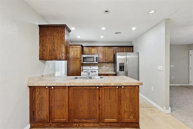 586 Seikel Dr, Choctaw, OK 73020 - kitchen with appliances with stainless steel finishes, a peninsula, a sink, light countertops, and backsplash