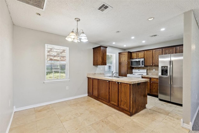 586 Seikel Dr, Choctaw, OK 73020 - kitchen with stainless steel appliances, baseboards, a chandelier, light countertops, and a peninsula