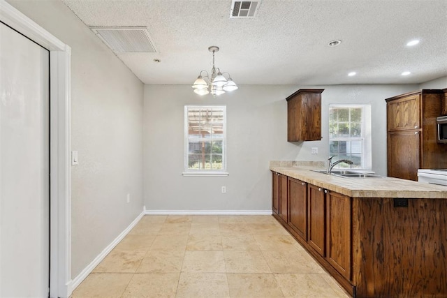 586 Seikel Dr, Choctaw, OK 73020 - kitchen featuring a sink, light countertops, a chandelier, stainless steel microwave, and baseboards