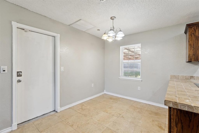 586 Seikel Dr, Choctaw, OK 73020 - unfurnished dining area with a chandelier, a textured ceiling, and baseboards