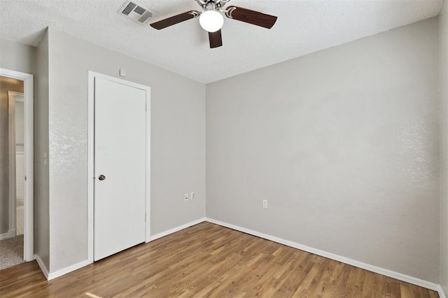 586 Seikel Dr, Choctaw, OK 73020 - unfurnished bedroom featuring wood finished floors, baseboards, a textured ceiling, and a ceiling fan