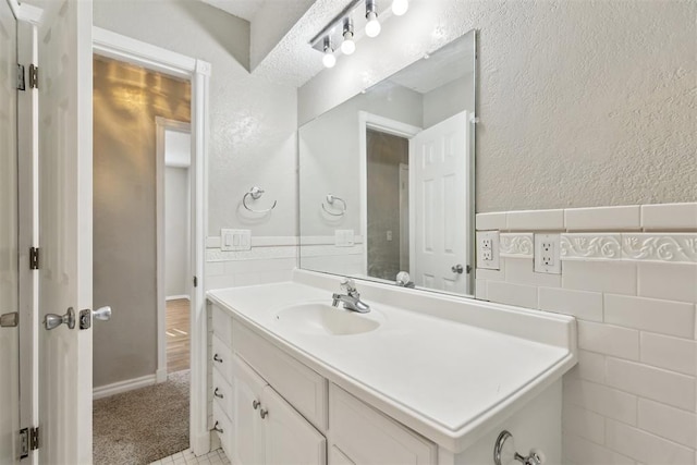 586 Seikel Dr, Choctaw, OK 73020 - bathroom with vanity, a wainscoted wall, a textured wall, and tile walls