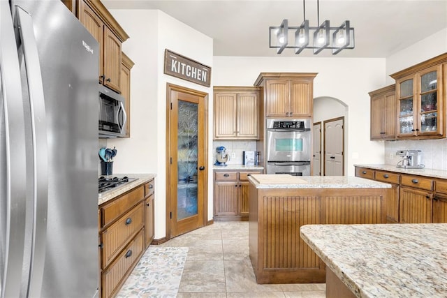 4679 Hillcrest Ln, Edmond, OK 73025 - kitchen with stainless steel appliances, tasteful backsplash, glass insert cabinets, and arched walkways