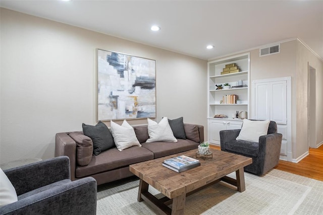 living area featuring recessed lighting, built in features, light wood finished floors, and visible vents