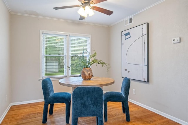 dining room with ceiling fan, visible vents, wood finished floors, baseboards, and ornamental molding