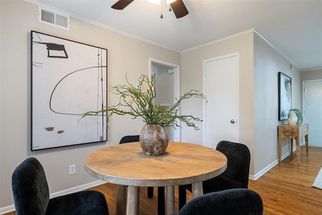 dining room with crown molding, a ceiling fan, wood finished floors, and visible vents
