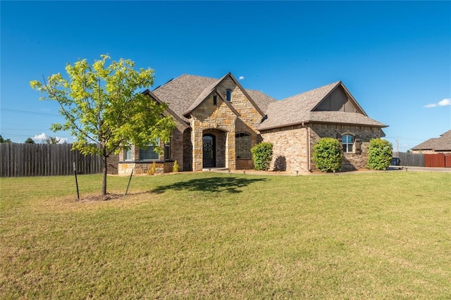 7217 SW 120th St, Oklahoma City, OK 73173 - french country home with a front yard, stone siding, brick siding, and fence
