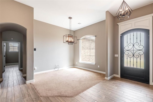 7217 SW 120th St, Oklahoma City, OK 73173 - foyer featuring arched walkways, an inviting chandelier, light wood-style flooring, and baseboards