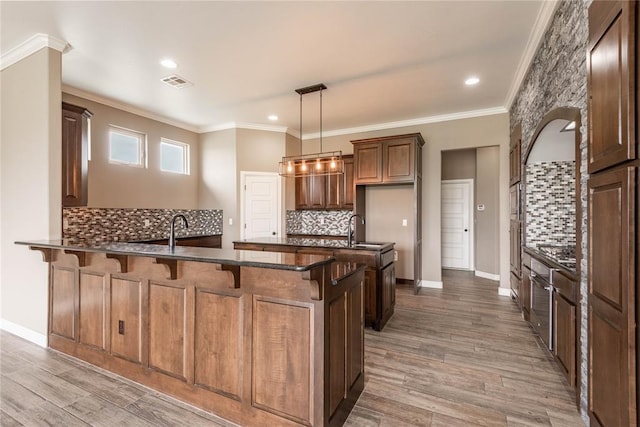 7217 SW 120th St, Oklahoma City, OK 73173 - kitchen featuring decorative backsplash, crown molding, visible vents, a kitchen bar, and a peninsula