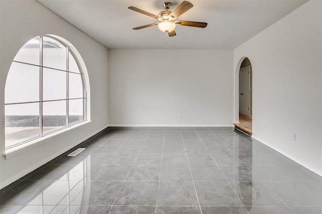 7705 Rumsey Rd, Oklahoma City, OK 73132 - unfurnished room with tile patterned flooring, a ceiling fan, arched walkways, and baseboards