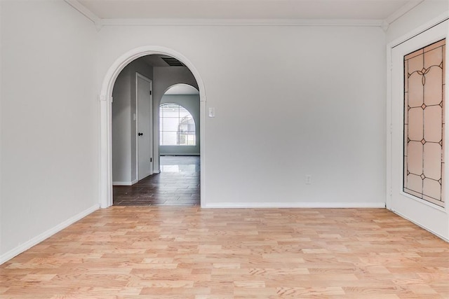 7705 Rumsey Rd, Oklahoma City, OK 73132 - empty room featuring crown molding, light wood-style flooring, baseboards, and arched walkways