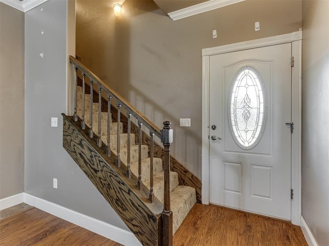entrance foyer featuring stairs, crown molding, baseboards, and wood finished floors