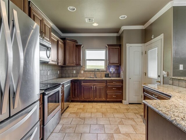 kitchen featuring backsplash, visible vents, light stone countertops, a sink, and stainless steel appliances