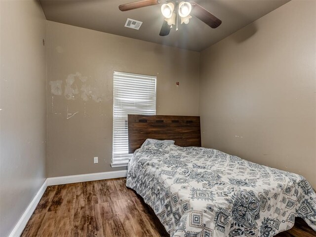 bedroom with a ceiling fan, baseboards, visible vents, and wood finished floors