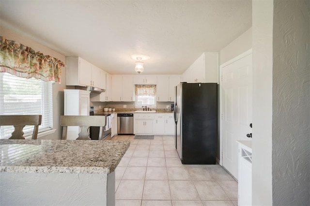 kitchen featuring light tile patterned floors, stainless steel appliances, under cabinet range hood, white cabinets, and a sink