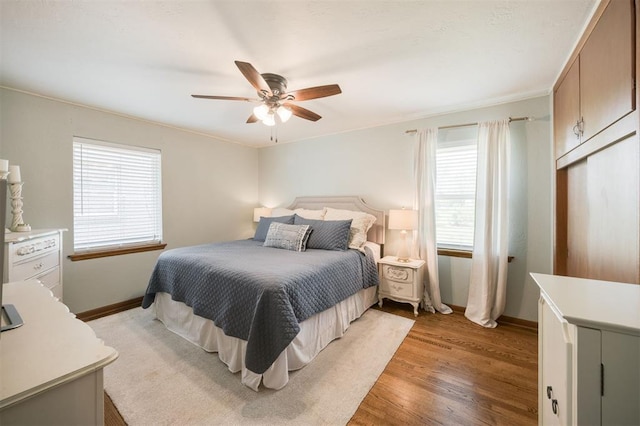 bedroom featuring ceiling fan, light wood finished floors, and baseboards
