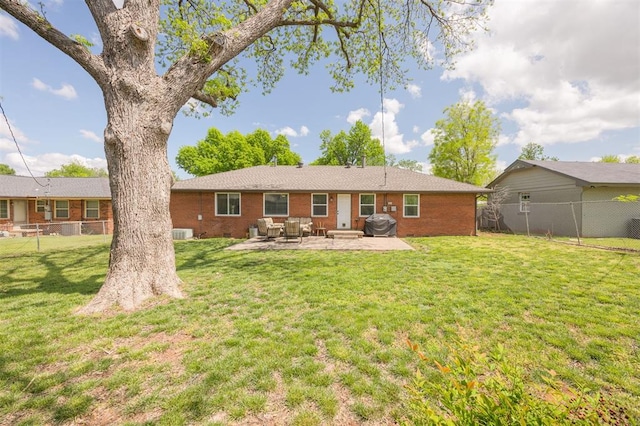 back of property with a patio, a lawn, brick siding, and fence